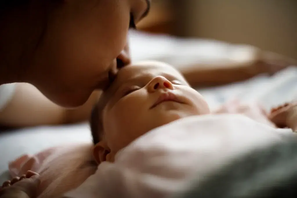 Parent kissing newborn during a soft close-up portrait at home - newborn photography prop - Dvotinst
