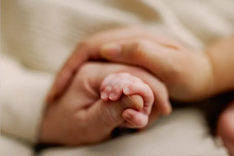 Newborn hand held gently by parent during a quiet detail portrait - newborn photography prop - Dvotinst
